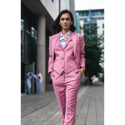 Woman in a pink suit walking outdoors on a city street.