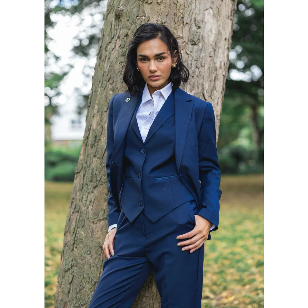 Woman in a blue suit standing next to a tree in an outdoor setting