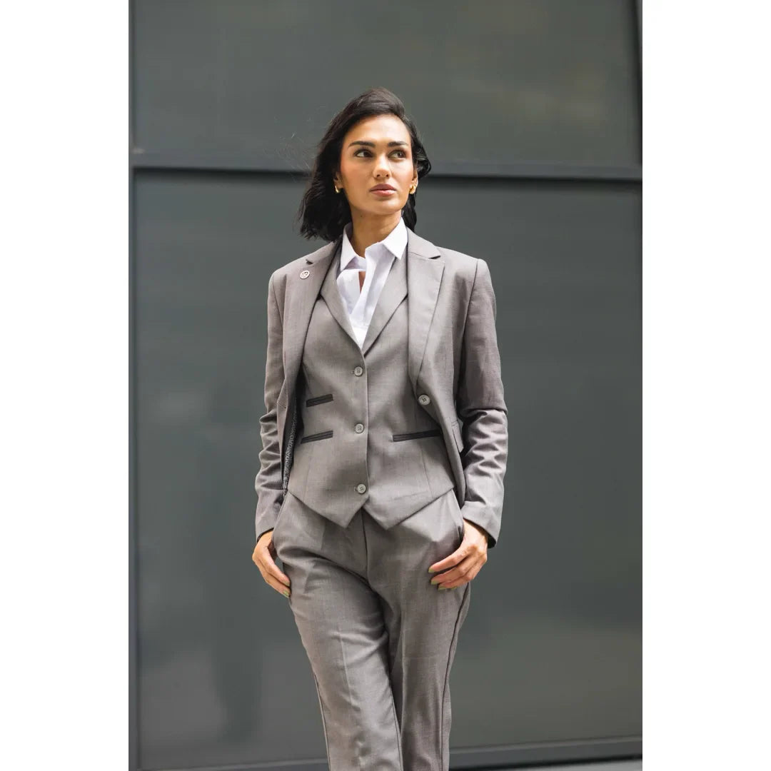 Woman wearing a gray suit standing against a plain background