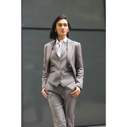 Woman wearing a gray suit standing against a plain background