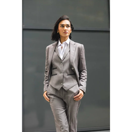 Woman wearing a gray suit standing against a plain background